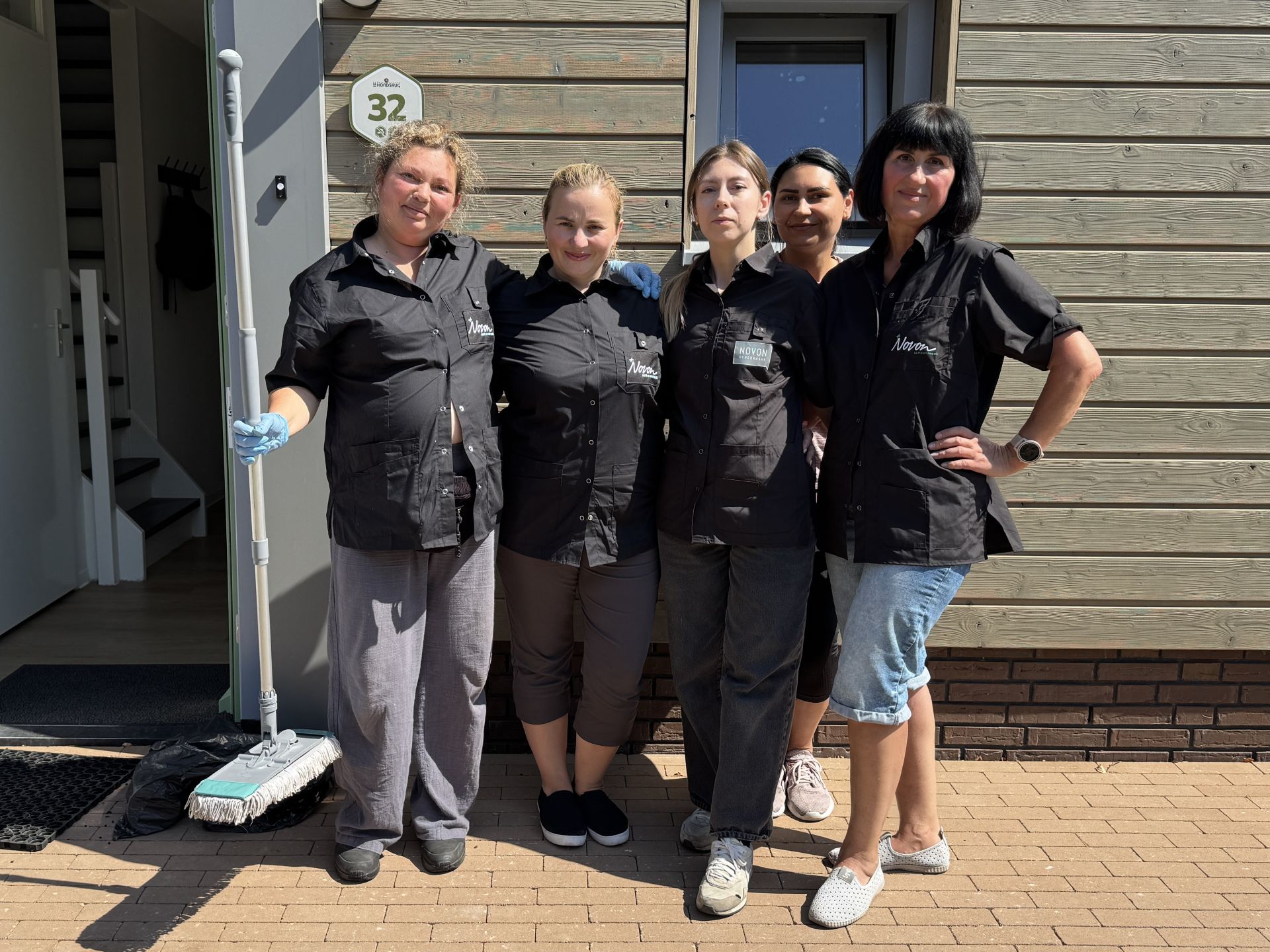 Een groep mensen poseert samen buiten naast een gebouw.
